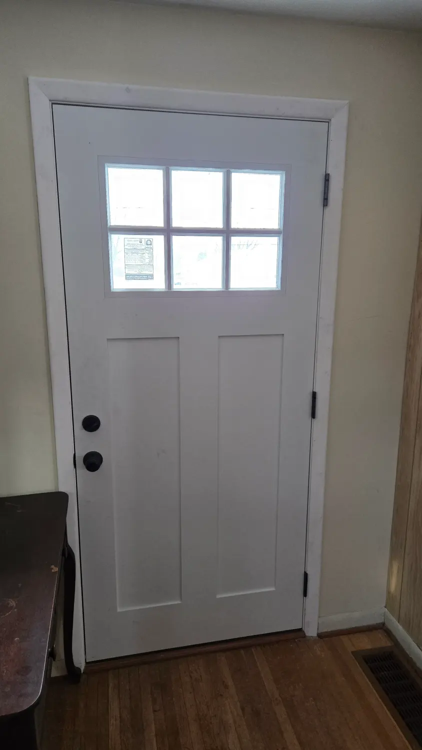 New white craftsman entry door with divided-lite window seen from inside by Drexler Home Services in Rochester NY