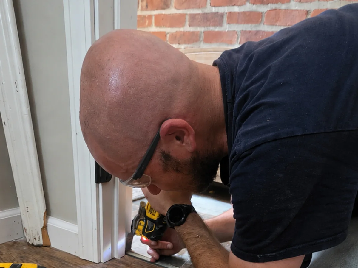 Adam Drexler fastening trim at an interior doorway